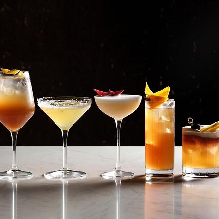 Middle Eight - Covent Garden - Preferred Hotels And Resorts Londra Esterno foto The photo features a selection of five different cocktails lined up on a marble surface. Each drink is served in a distinct glass, showcasing a variety of colors and garnishes. 

1. The first cocktail is in a large wine glass, with a gradient color f
