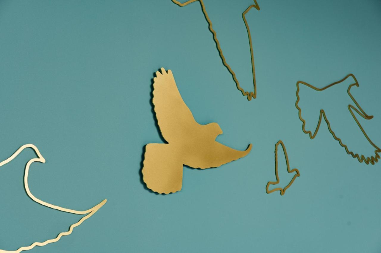 Middle Eight - Covent Garden - Preferred Hotels And Resorts Londra Esterno foto The photo shows a collection of metallic gold bird silhouettes against a solid turquoise background. The birds are depicted in various positions and styles, showcasing different species and flight postures. Some silhouettes are more detailed, while o