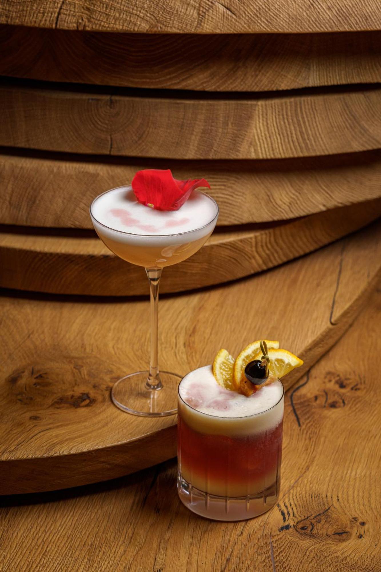 Middle Eight - Covent Garden - Preferred Hotels And Resorts Londra Esterno foto The photo showcases two elegant cocktails arranged against a warm wooden backdrop. 

1. The first cocktail is served in a classic coupe glass. It has a frothy, pale hue, topped with a vibrant red flower petal, adding a touch of sophistication. 

2. T